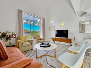 Ein modernes Wohnzimmer mit Flachbildfernseher, Couchtisch und gemütlicher Sitzgruppe.