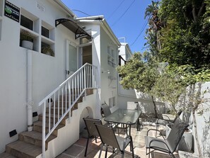 A white building with a staircase, outdoor seating area, and a tree. - Two Bed Home Fresnaye Secure Spacious BBQ (Cape Town)