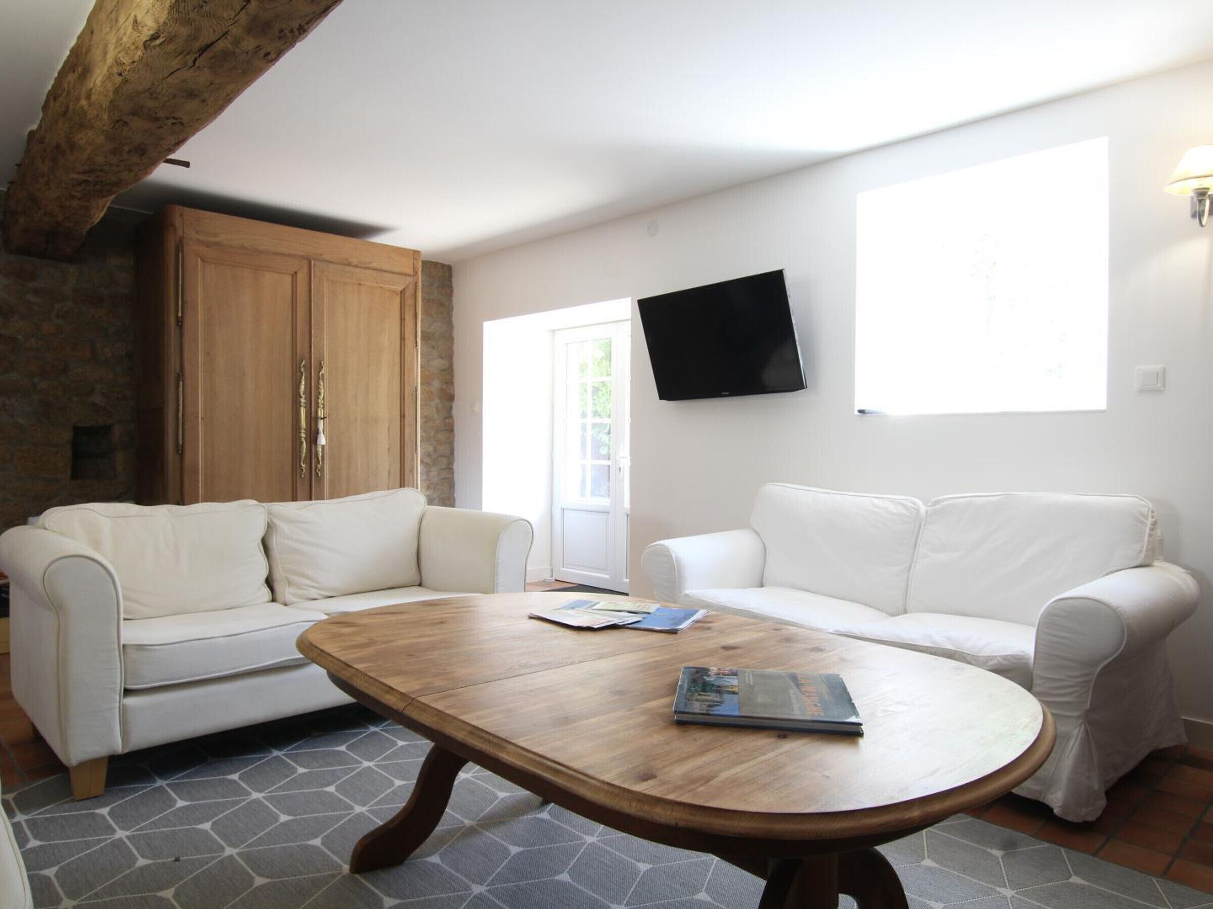 A living room with two white sofas, a wooden coffee table, and a stone-patterned floor.