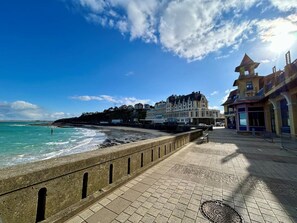 A seaside promenade with a stone walkway, a view of the ocean, and buildings in the background. - House with parking, pets welcome - 7 guests (Le Val-Saint-Père)