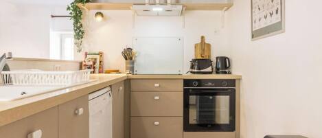 A compact kitchen with a built-in dishwasher, a stove, and a microwave.