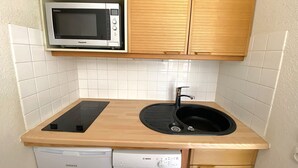 Kompakti keittiö, jossa on mikroaaltouuni, pesuallas ja astianpesukone.