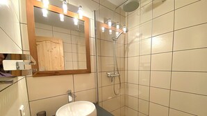 Kylpyhuone, jossa on pyöreä pesuallas, peili ja suihku.