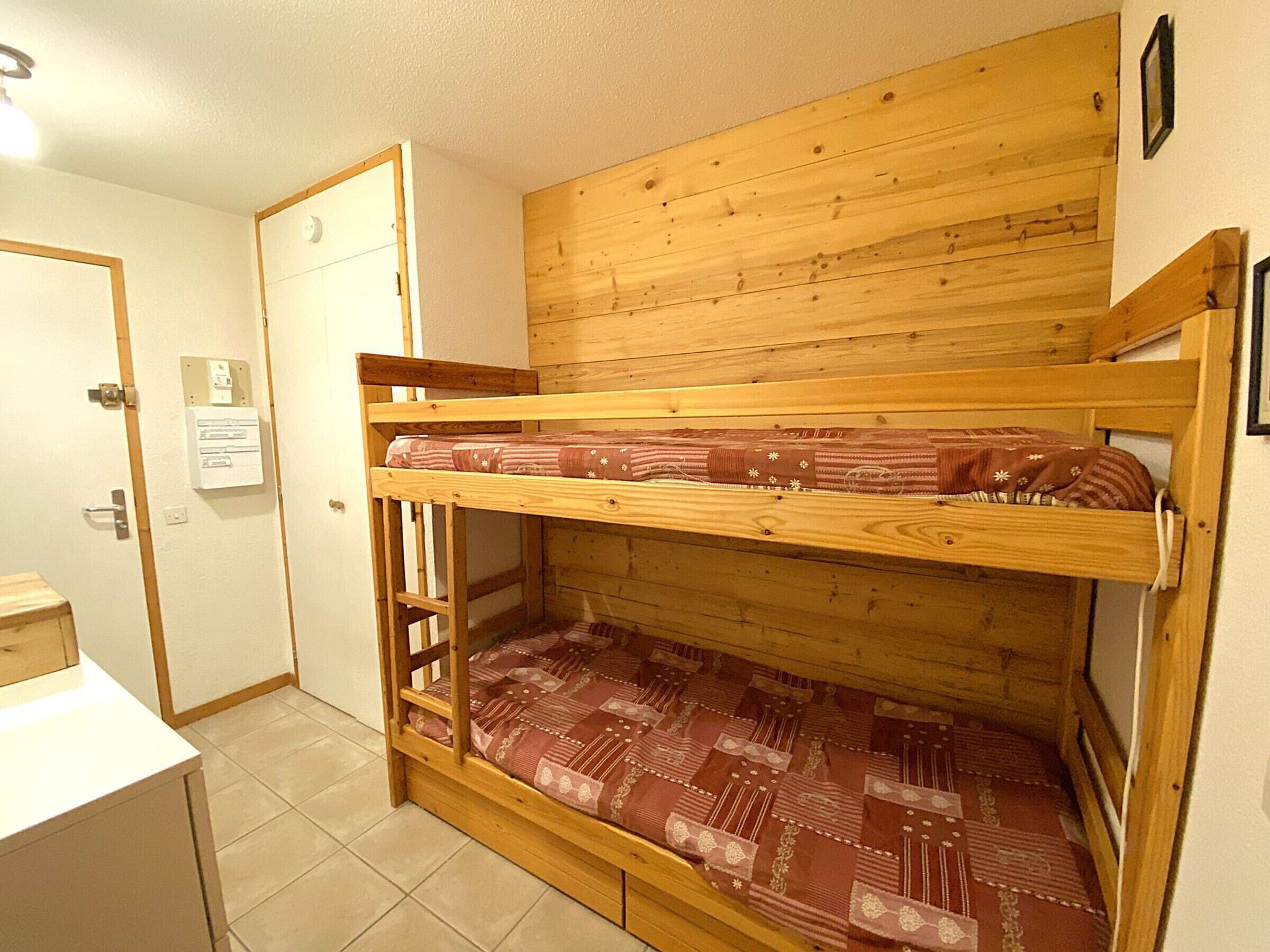 Una cama litera con cabecera de madera y una cama inferior con colchón estampado.