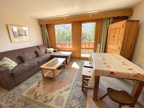 A cozy living room with a sofa, a wooden coffee table, and a patterned rug. - Cozy studio, mountain view - 4 guests (Méribel)