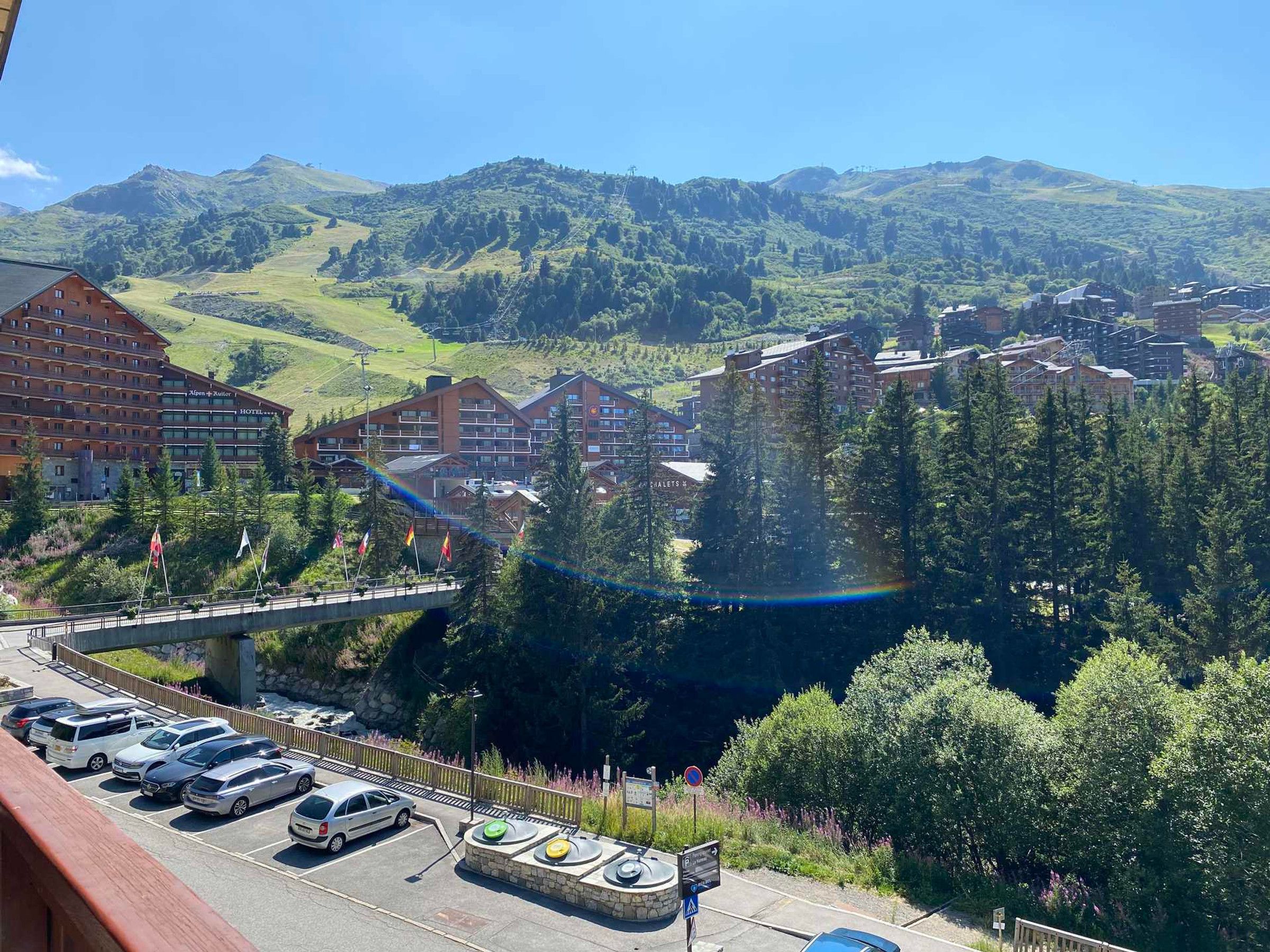 A hotel with multiple buildings, a parking area, and a mountainous backdrop.
