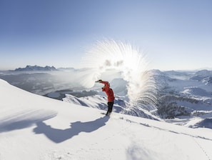 A person in a red jacket standing on a snowy mountain with a clear sky. - Superior Penthouse # A11 with 4 bedrooms and sauna (Söll)