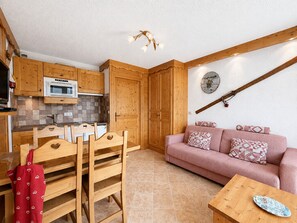 Eine kleine Küche mit Holzausstattung, einer Mikrowelle und einer Essecke mit Holztisch und Stühlen.