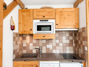 Eine kompakte Küche mit Holzausstattung, einem Backofen, einer Spüle und einem Geschirrspüler von Bosch.