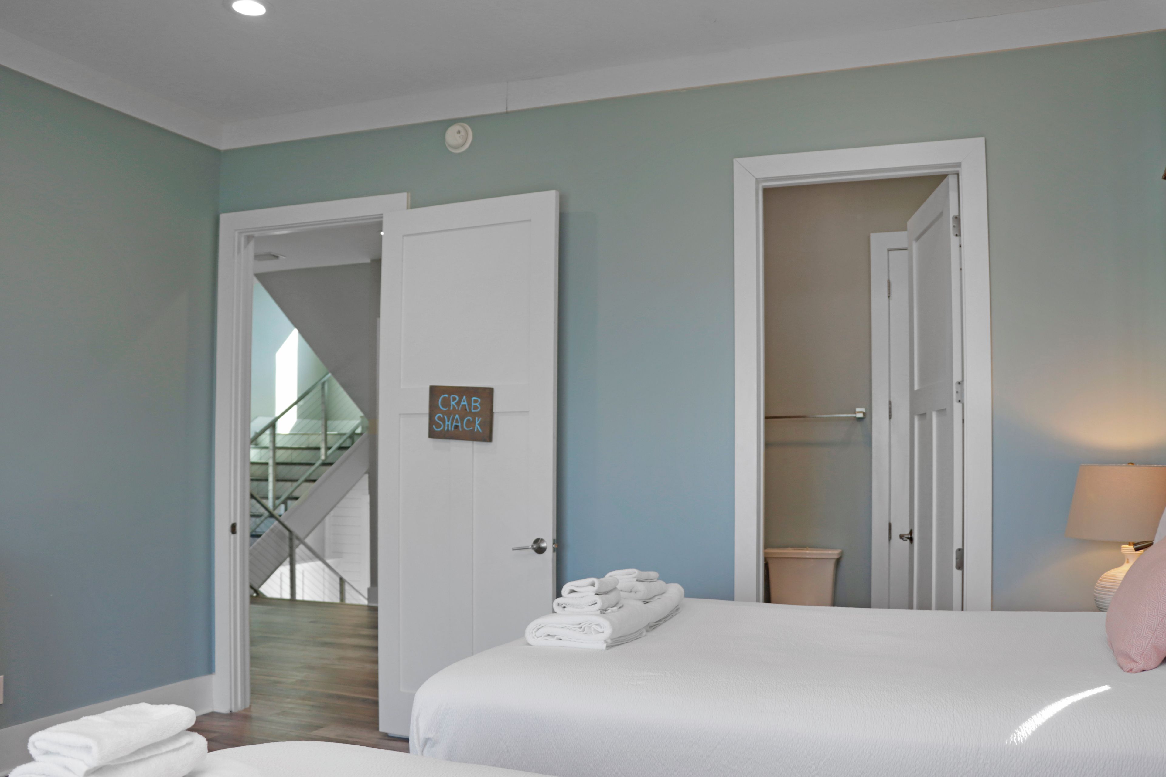 Een hotelkamer met twee bedden, een badkamer en een trap naar een verdieping hoger.