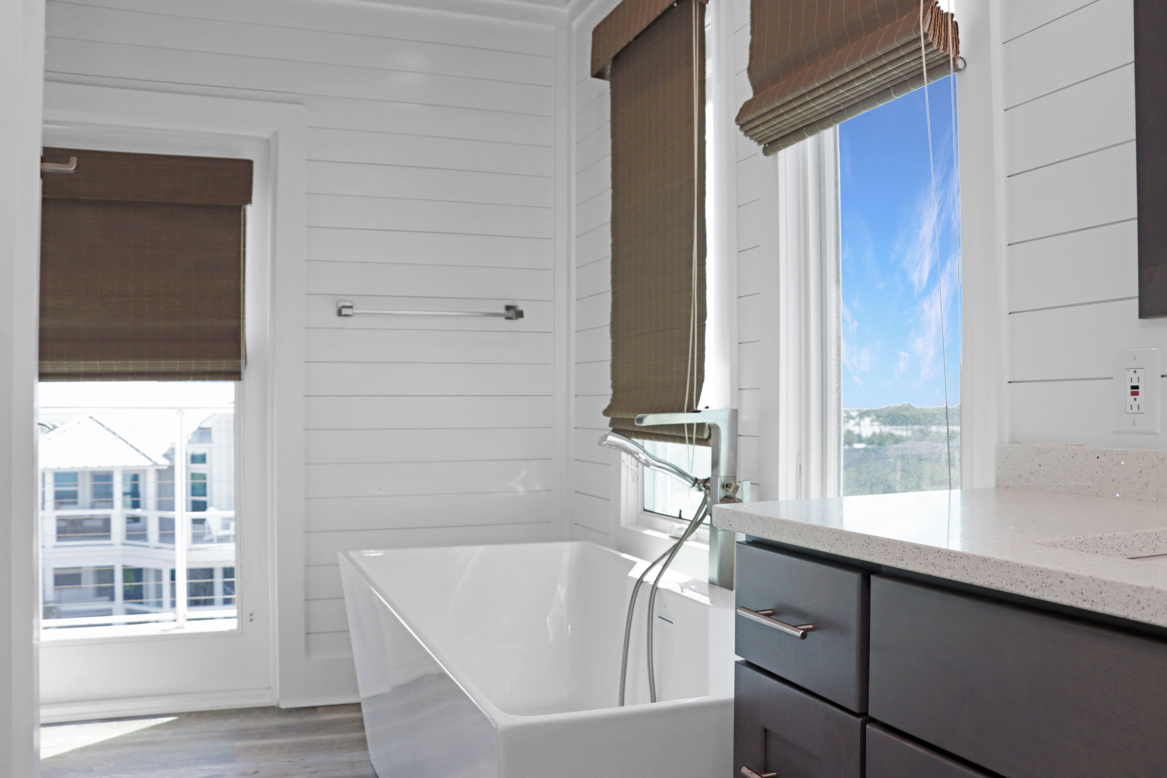Une salle de bain moderne avec une baignoire, une fenêtre donnant sur un beau paysage et une porte dotée d’un porte-serviettes.