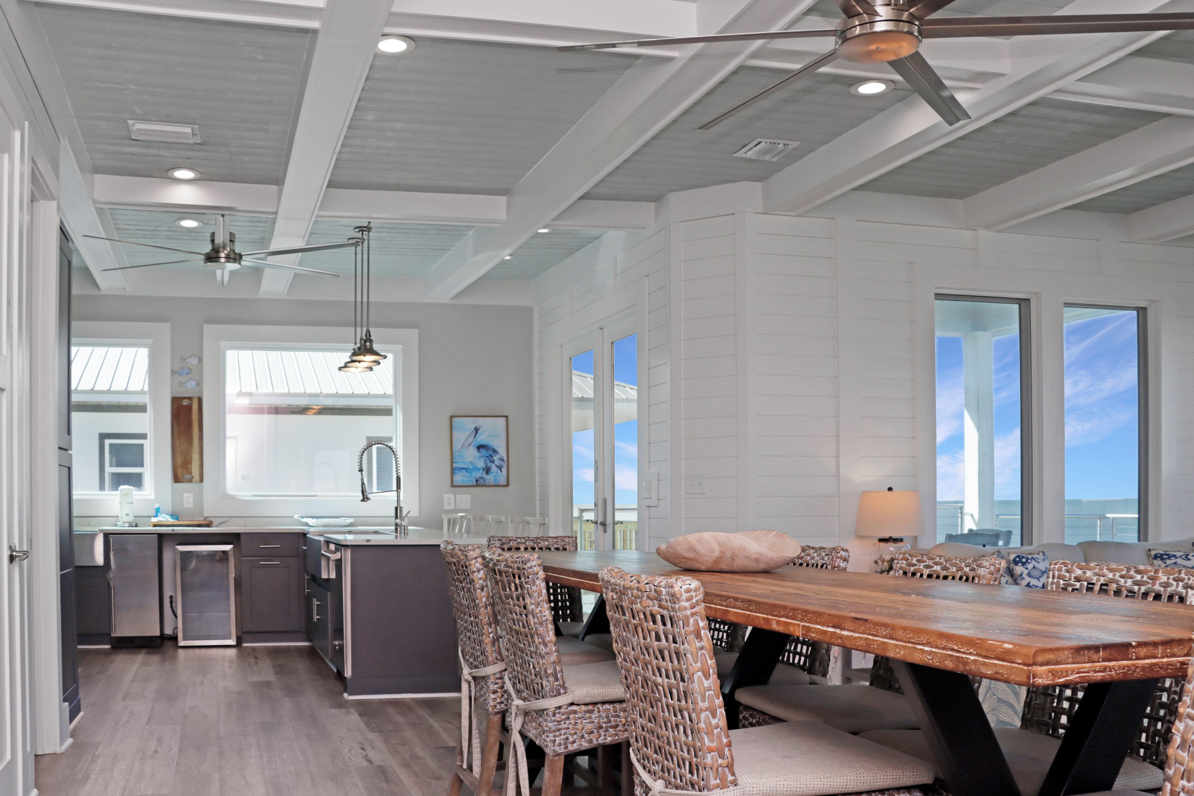 A spacious kitchen with a dining area, large windows, and a ceiling fan.