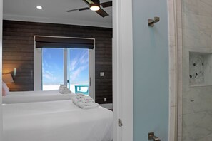 A hotel room with a bed, a ceiling fan, a shower, and a view of the beach. - 🌊Singing Waves | Stunning Beachfront | Community Pool | Pet Friendly (Cape San Blas)