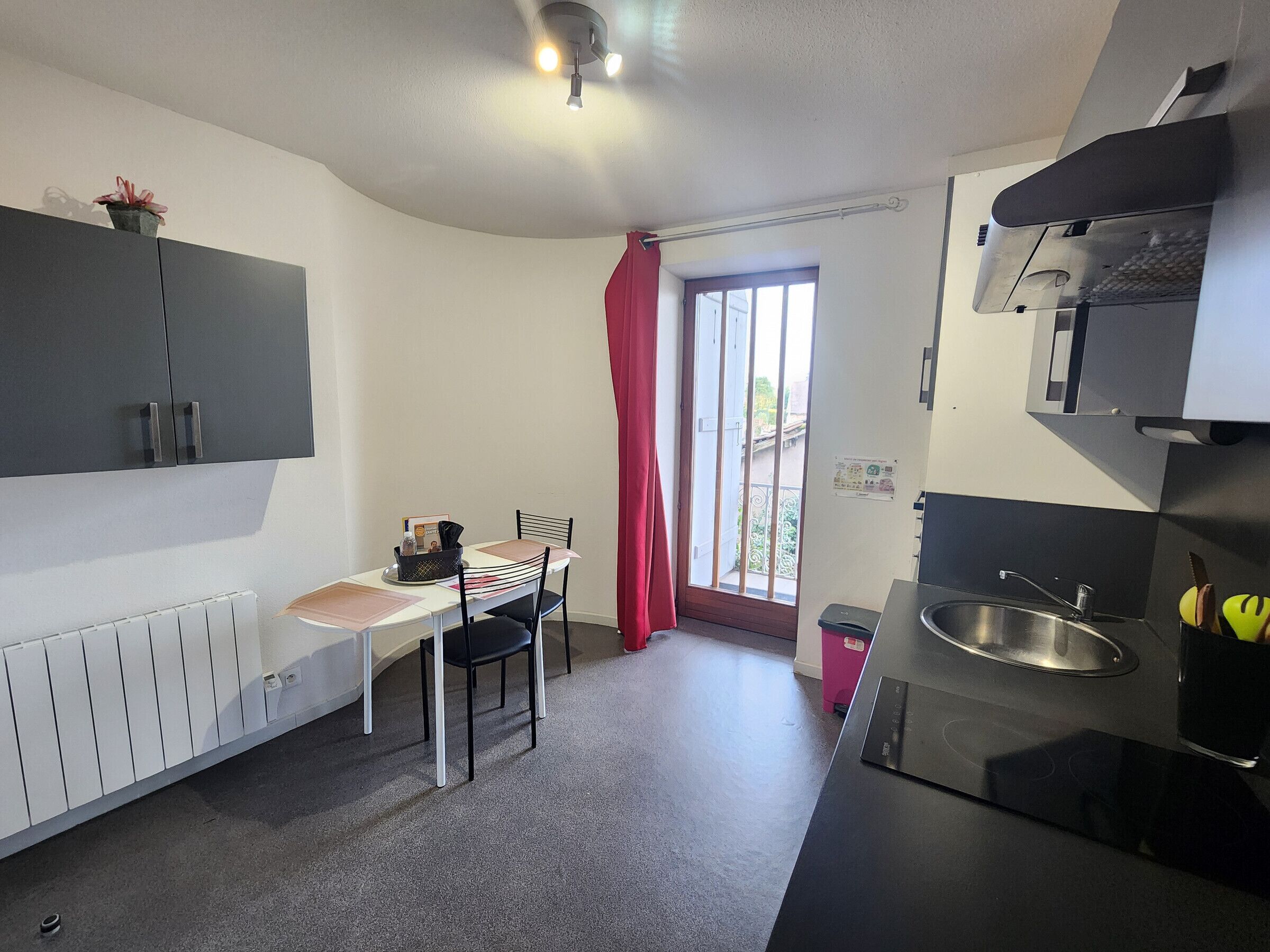 Une cuisine de taille réduite comprenant une table à manger, des chaises, un réfrigérateur et un évier.
