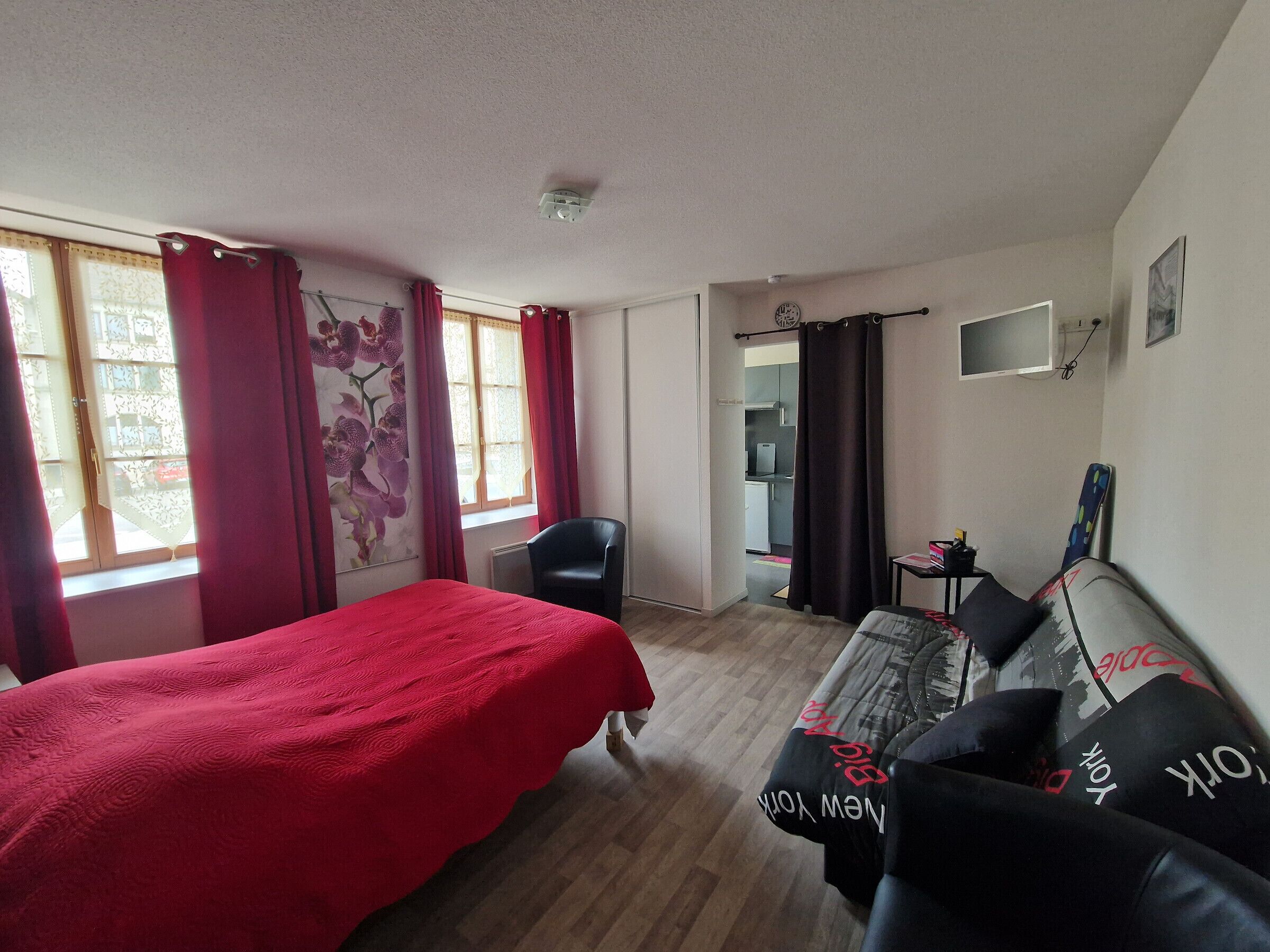 Una camera d'albergo con un letto, un divano, una poltrona, una TV e angolo cottura.