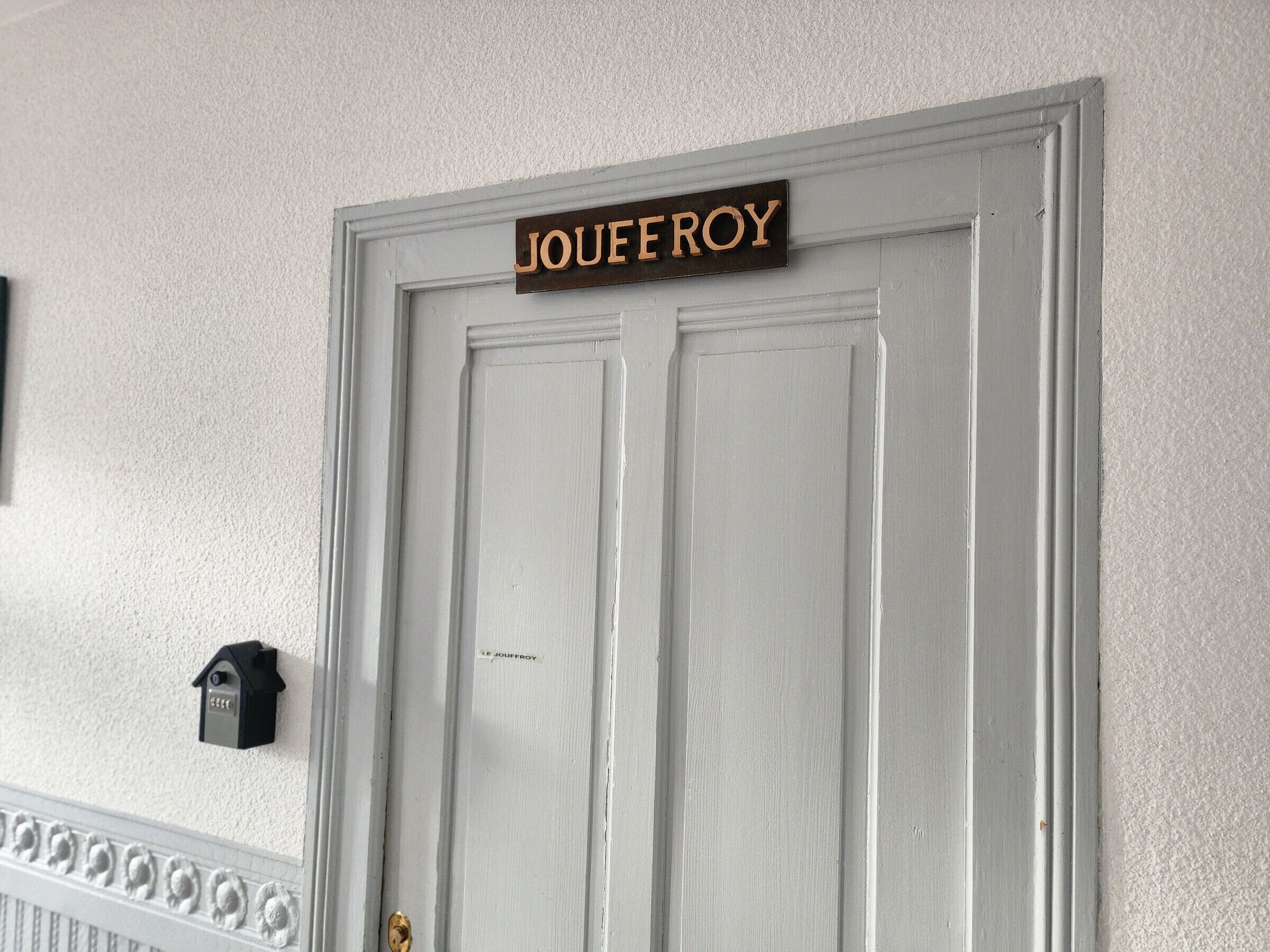 Une porte blanche avec une enseigne au-dessus portant l’inscription « JOUFFROY ».