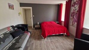 Une pièce comprenant un lit, un canapé, une petite table et une fenêtre avec des rideaux.