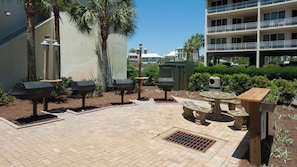 An outdoor patio area with a brick floor, outdoor grills, and a round table with chairs. - 2BR Gulf-Front | Pool, Hot Tub & Direct Beach Access + Attraction Tickets! (Santa Rosa Beach)