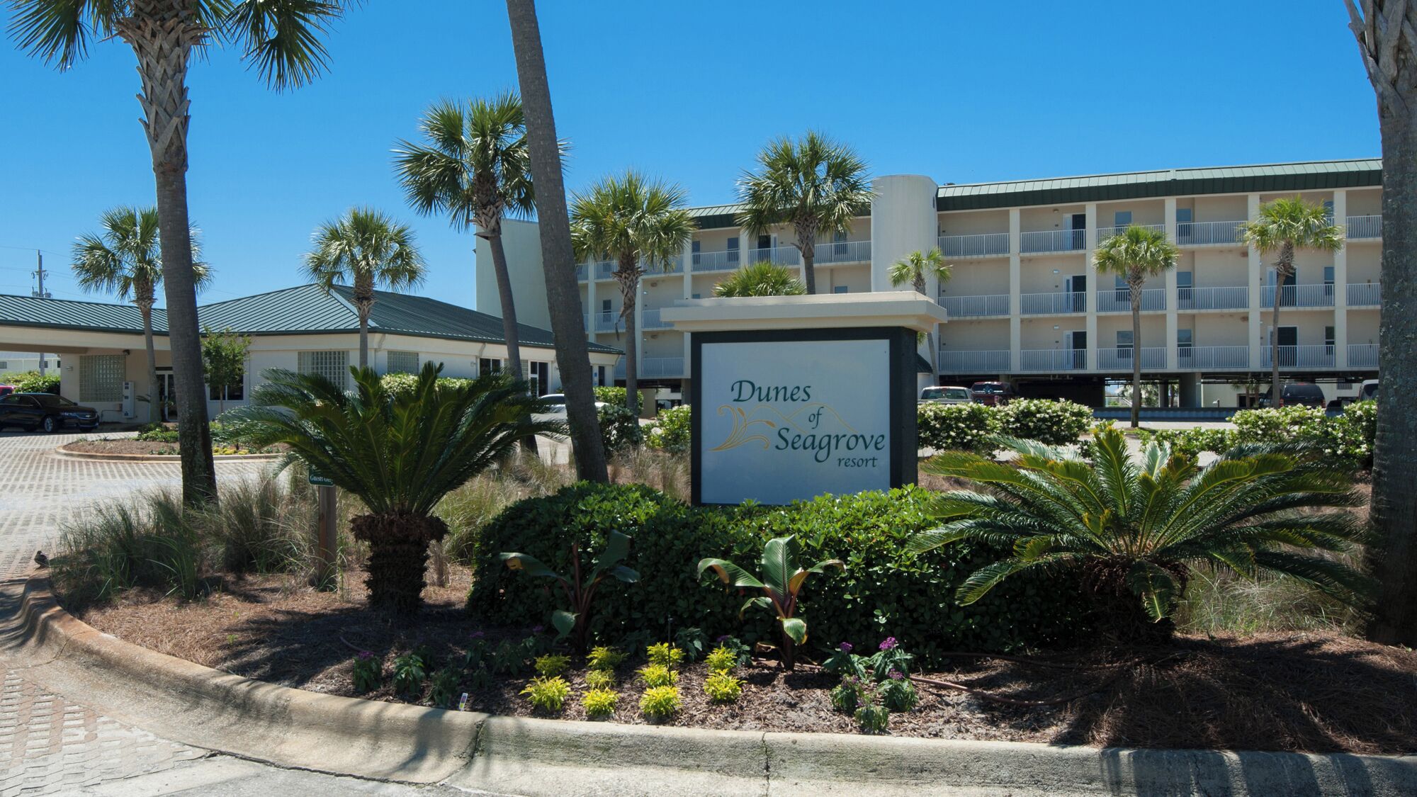 Cartell del Dunes of Seagrave Resort, amb un edifici al fons.