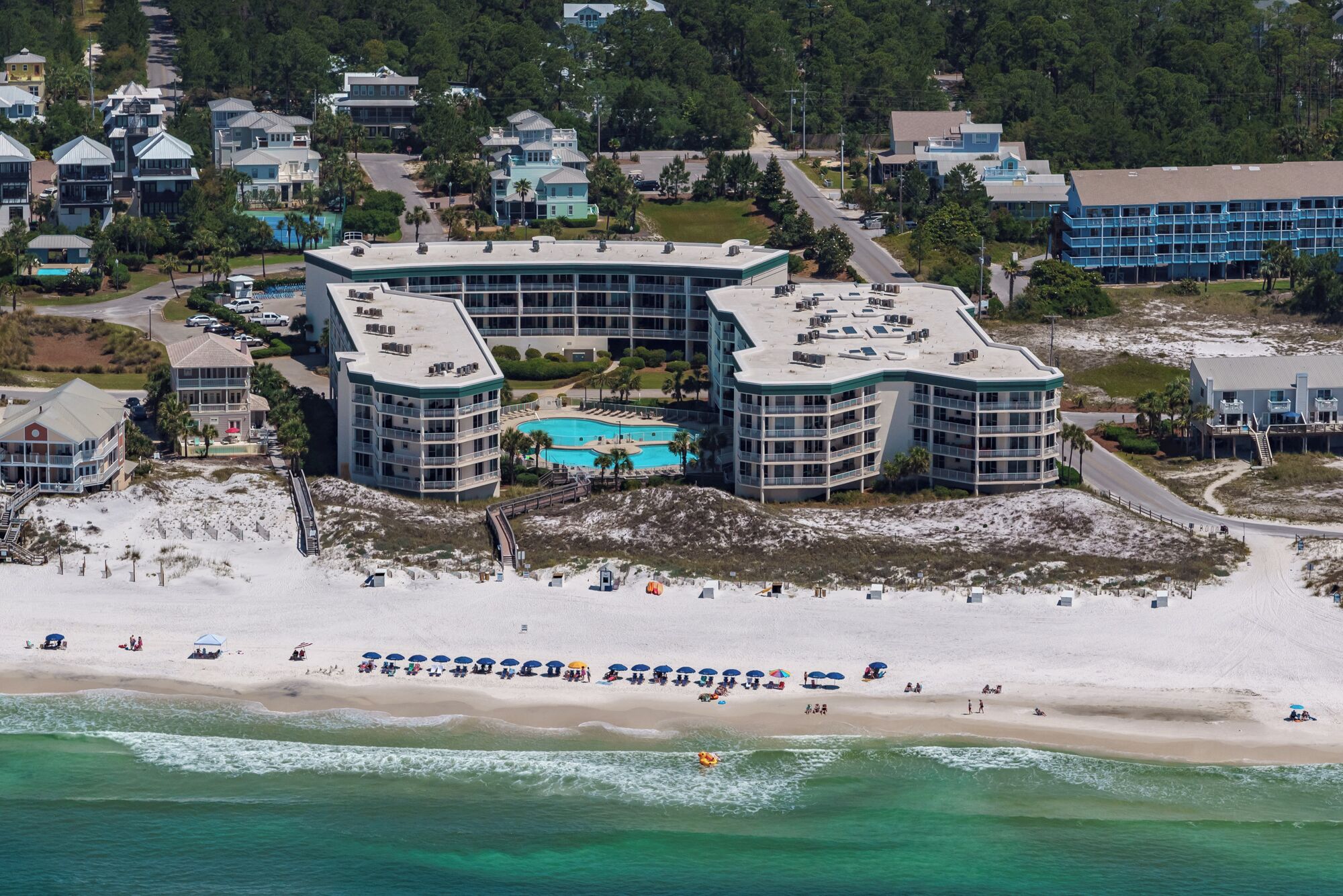 A coastal hotel with multiple buildings, a beachfront, and a swimming pool.