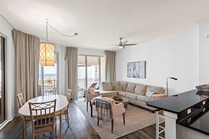 Ein modernes Wohnzimmer mit einer Couch, einem Esstisch, Stühlen und Blick aufs Meer.