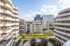 Ein mehrgeschossiges Wohngebäude mit Balkonen, einem begrünten Innenhof und moderner Architektur.