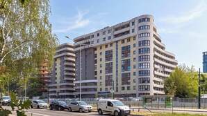 Un edificio residencial de varios pisos con balcones y un estacionamiento al frente.