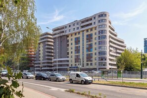 Ein mehrstöckiges Wohngebäude mit Balkonen und einem Parkplatz davor.