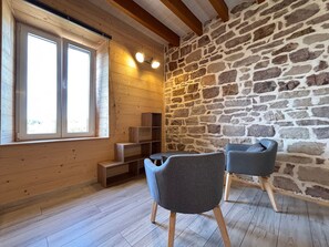 A room with wooden walls, a stone wall, a window, and two chairs. - Charming apartment in Luxeuil-les-Bains (Luxeuil-les-Bains)