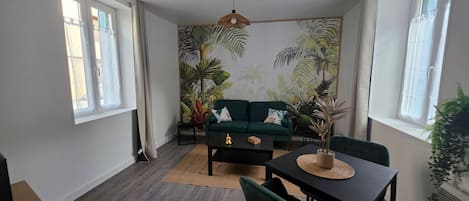 Una habitación con un sofá verde, una mesa de comedor y un ventilador de techo.