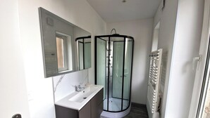 A modern bathroom with a glass shower enclosure, a white sink, and a large mirror. - Renovated cottage near thermal baths (Luxeuil-les-Bains)