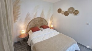 A bedroom with a bed, a nightstand, a wall-mounted lamp, and decorative wall art. - Renovated cottage near thermal baths (Luxeuil-les-Bains)