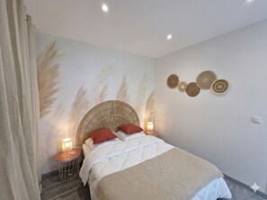 Ein Schlafzimmer mit einem Bett, einem Nachttisch, einer Wandlampe und Wanddekoration.