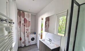 Un baño pequeño con lavadora, lavamanos y ventana.