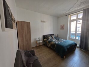 Ein Schlafzimmer mit Bett, Nachttisch, Holzschrank und einem Fenster mit Vorhängen.