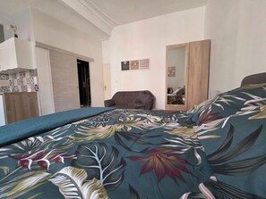 Ein Schlafzimmer mit einem Bett, einem Kleiderschrank, einem Sessel und einem Spiegel.