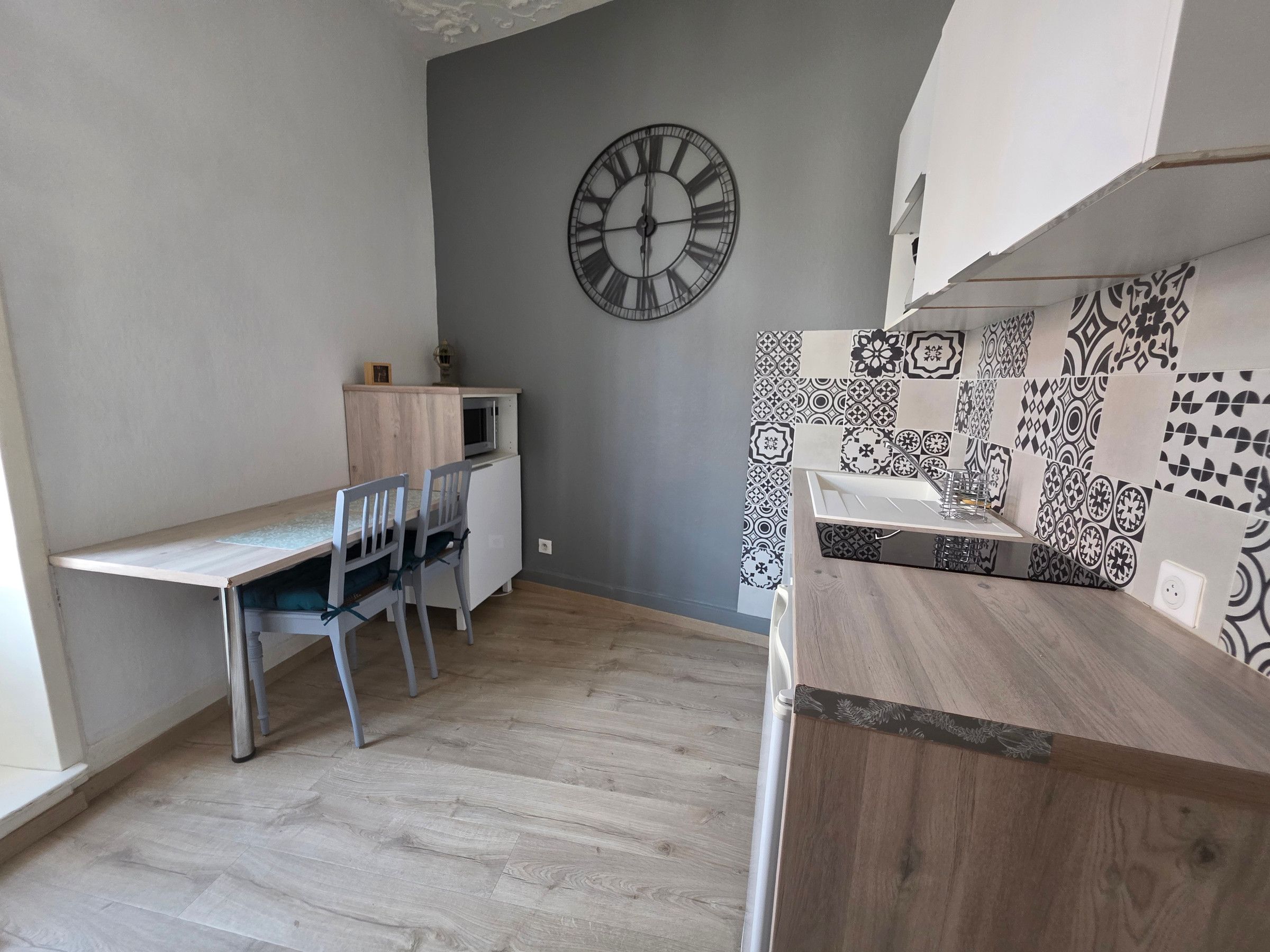Une cuisine compacte dotée d’un plan de travail en bois, d’un four à micro-ondes et d’une horloge murale.