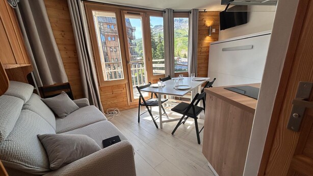 A compact living space with a sofa, dining table, chairs, and a kitchenette. - Cozy apartment with balcony - 4 guests (Avoriaz)
