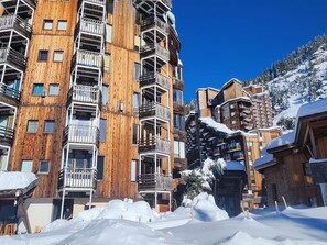 Un immeuble en bois à plusieurs étages, doté de balcons et entouré de neige.