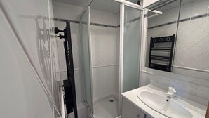 A modern bathroom with a glass-enclosed shower, a white sink, and a mirror above the sink. - Cozy apartment with balcony - 4 guests (Avoriaz)
