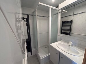Ein modernes Badezimmer mit einer Duschkabine aus Glas, einem weißen Waschbecken und einem Spiegel darüber.