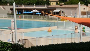 Ein Schwimmbecken mit Rettungsschwimmerstation, Sonnenschirm und einem kleinen aufblasbaren Spielzeug.