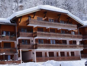 A multi-story wooden chalet with balconies, surrounded by snow-covered trees. - Bright apartment, pets welcome - 6 guests (Morzine)