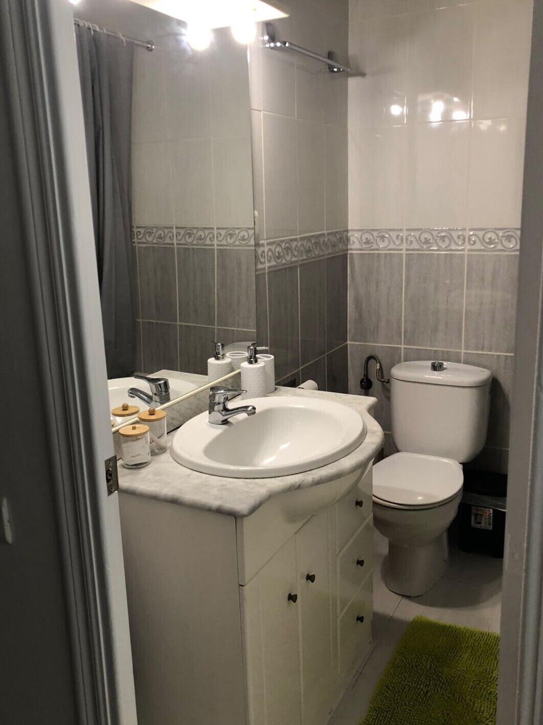 Een badkamer met een wit wastafelmeubel, toilet en kastjes.