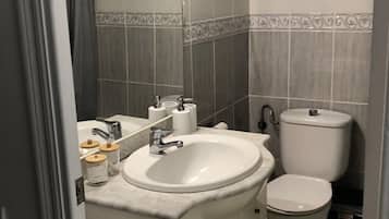 Een badkamer met een wit wastafelmeubel, toilet en kastjes.