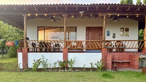 Una casa con un porche cubierto, una terraza de madera y un pequeño jardín.