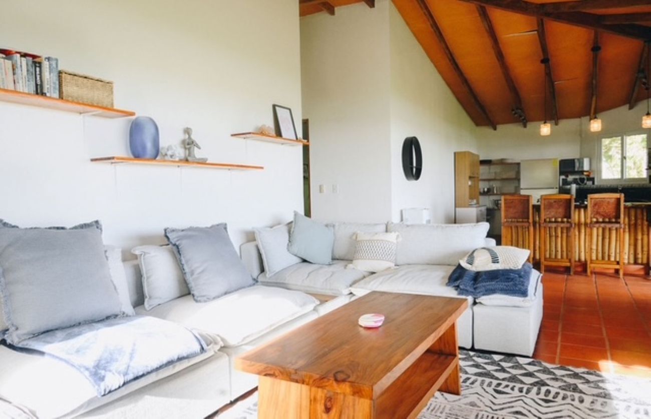 Sala de estar con sofá, mesa de centro y área de cocina al fondo.