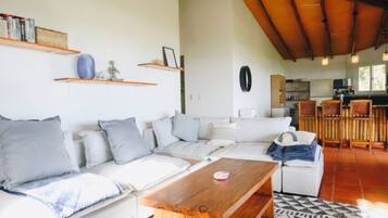 Sala de estar con sofá, mesa de centro y área de cocina al fondo.