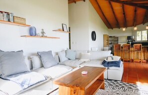 Sala de estar com sofá, mesinha de centro e cozinha ao fundo.