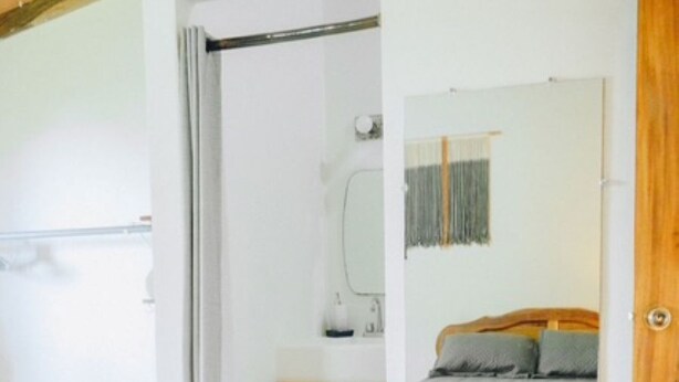 Un dormitorio con una cama, un armario de madera, un espejo y una puerta.